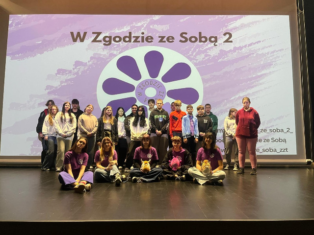  osoby w szeregu przed pla...